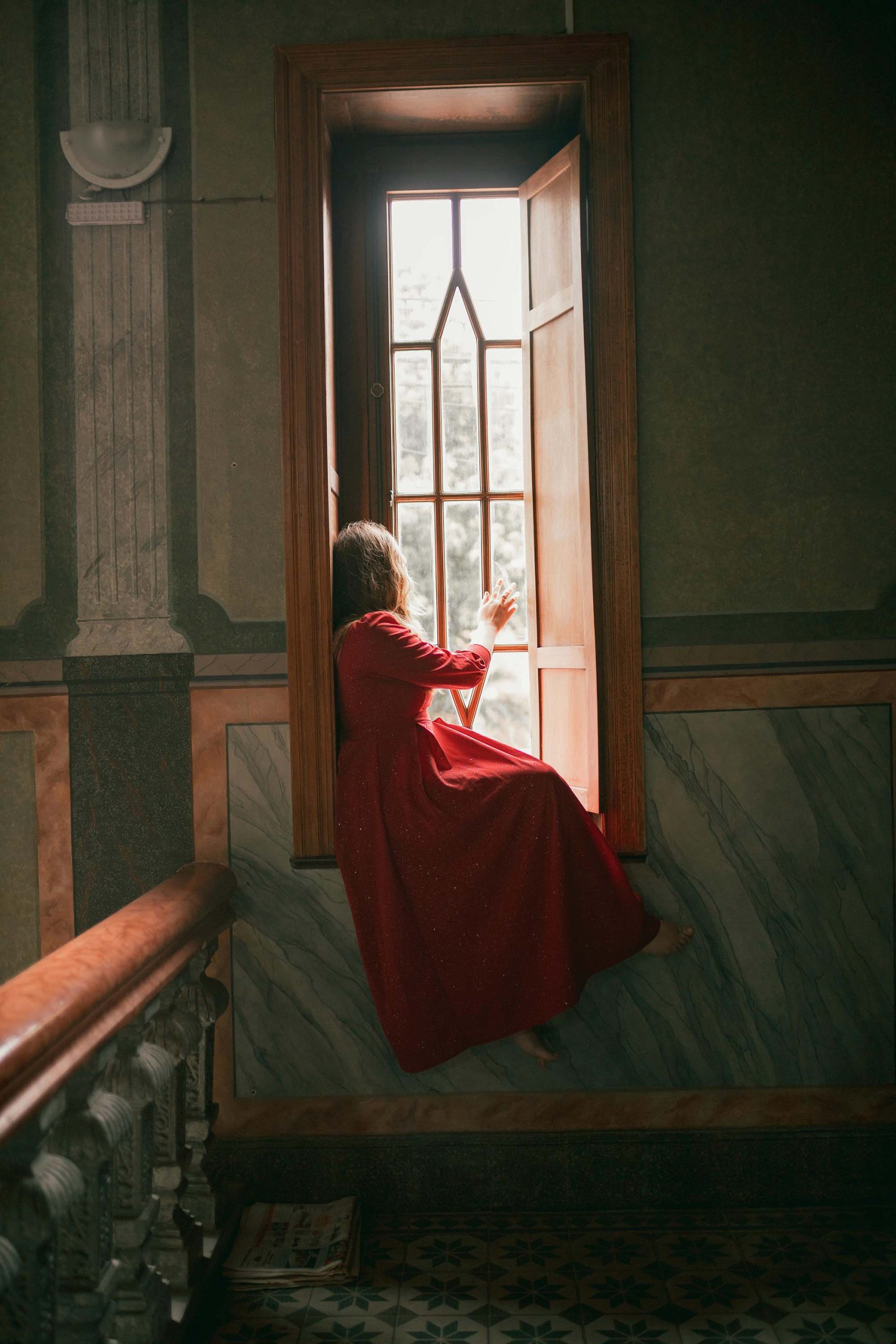 cô gái mặc váy đỏ ngồi bên cửa sổ thu hút năng lượng tích cực